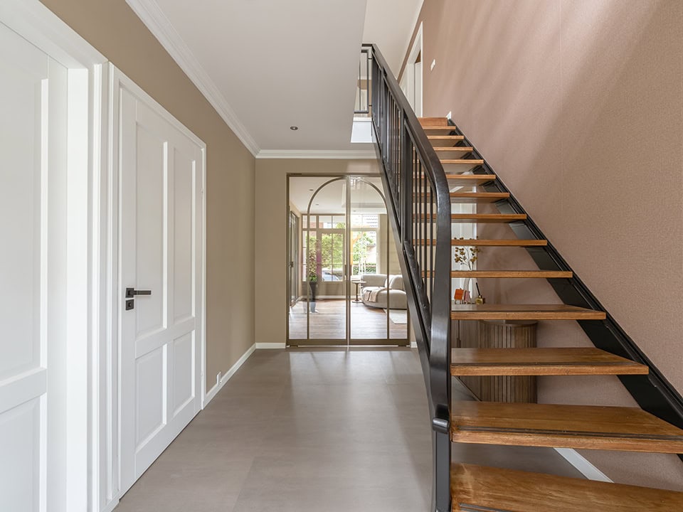 Binnenruimte met stalen trap en glazen schuifdeur, modern interieur, lichte kleuren, hoogwaardige afwerking, geschikt voor woning of kantoor.