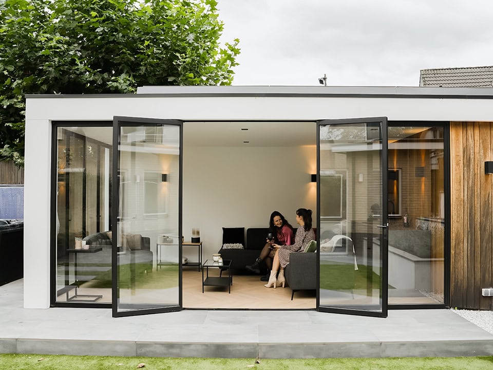 Luxe woonkamer met grote stalen schuifdeuren die openklappen naar de tuin, ideaal voor binnen-buiten leefruimte en modern design.