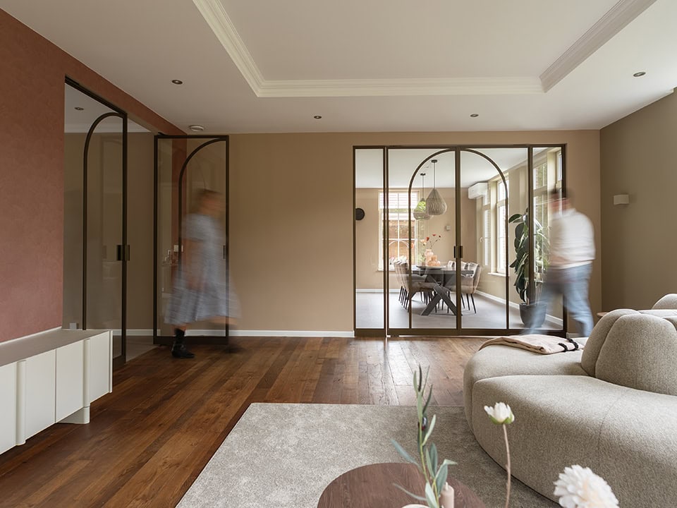 Binnenruimte met moderne stalen scheidingswand en glazen deuren, houten vloer, en comfortabele zithoek, perfect voor stijlvolle indeling en privacy.