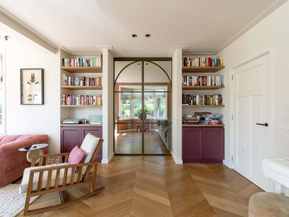 Stijlvolle woonkamer met ingebouwde boekenkasten, glazen schuifdeur en comfortabele zithoek, perfect voor een modern interieur.