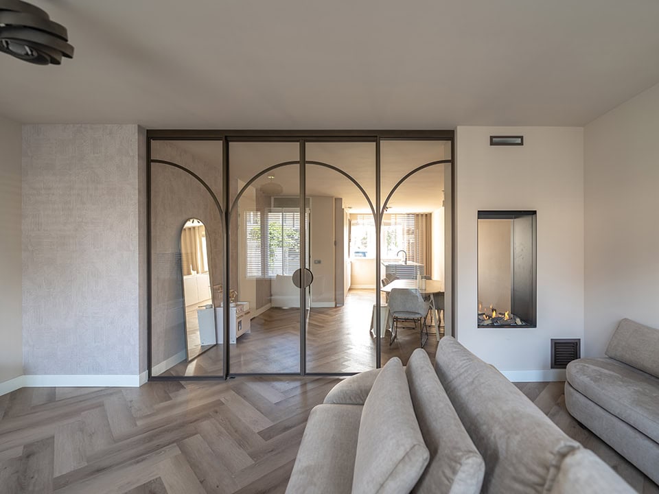 Hoogwaardige stalen deuren en wanden op maat in een modern interieur, scheiding tussen woonkamer en eetkamer, natuurlijke lichtinval, stijlvolle afwerking.