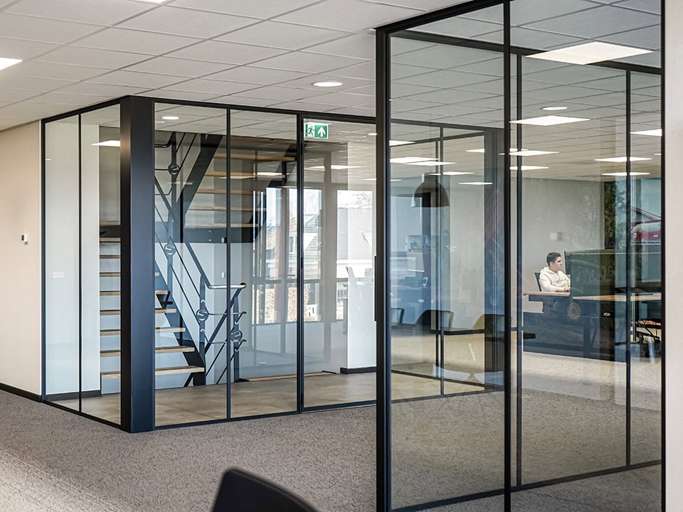 Interieur van een modern kantoor met glazen wanden en stalen deuren, geschikt voor kantoorruimtes en vergaderruimtes, met een strakke en professionele uitstraling.