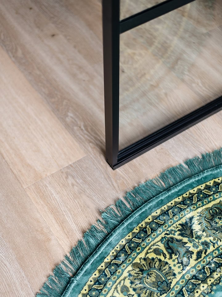 Moderne stalen scheidingswand met glazen panelen in een interieur, geschikt voor kantoor of woonruimte, met een houten vloer en een decoratieve ronde tapijt.
