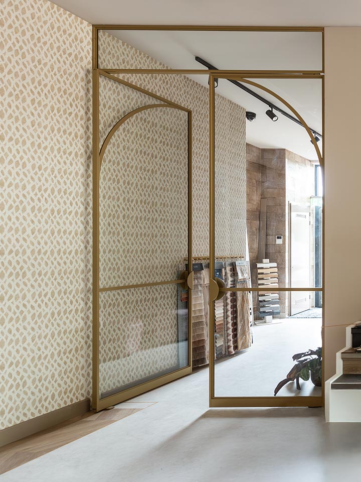 Luxe stalen schuifdeur met goudkleurige afwerking en glazen panelen, perfect voor moderne interieurs en op maat gemaakte deuren.