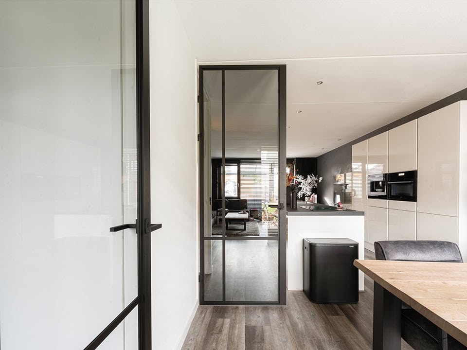 Moderne stalen deur met glas tussen woonkamer en keuken, op maat gemaakt, passend bij hoogwaardige stalen deuren en wanden, geschikt voor moderne interieurs.