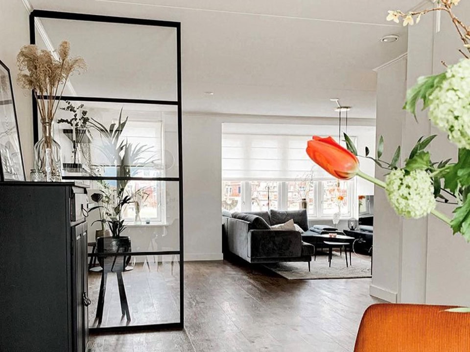 Lichte en moderne interieurindeling met stalen Crittall room dividers, grote ramen en comfortabele zithoek in een eigentijdse woonkamer.