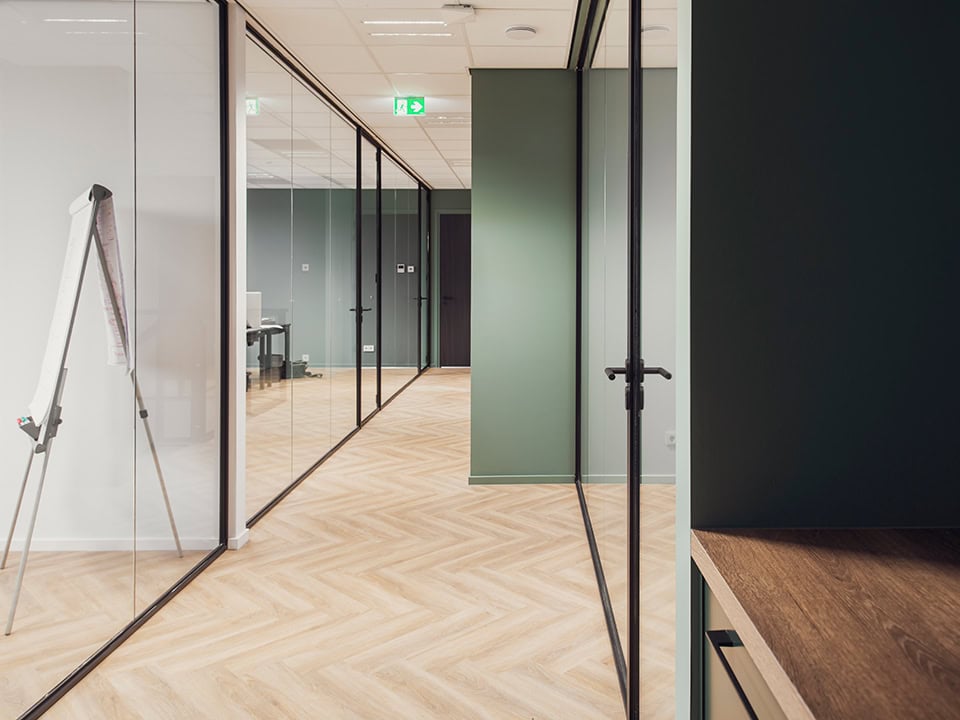 Strakke kantoorwanden met stalen kozijnen en glazen scheidingswanden voor een moderne kantooromgeving, op maat gemaakt door Aluwdoors.