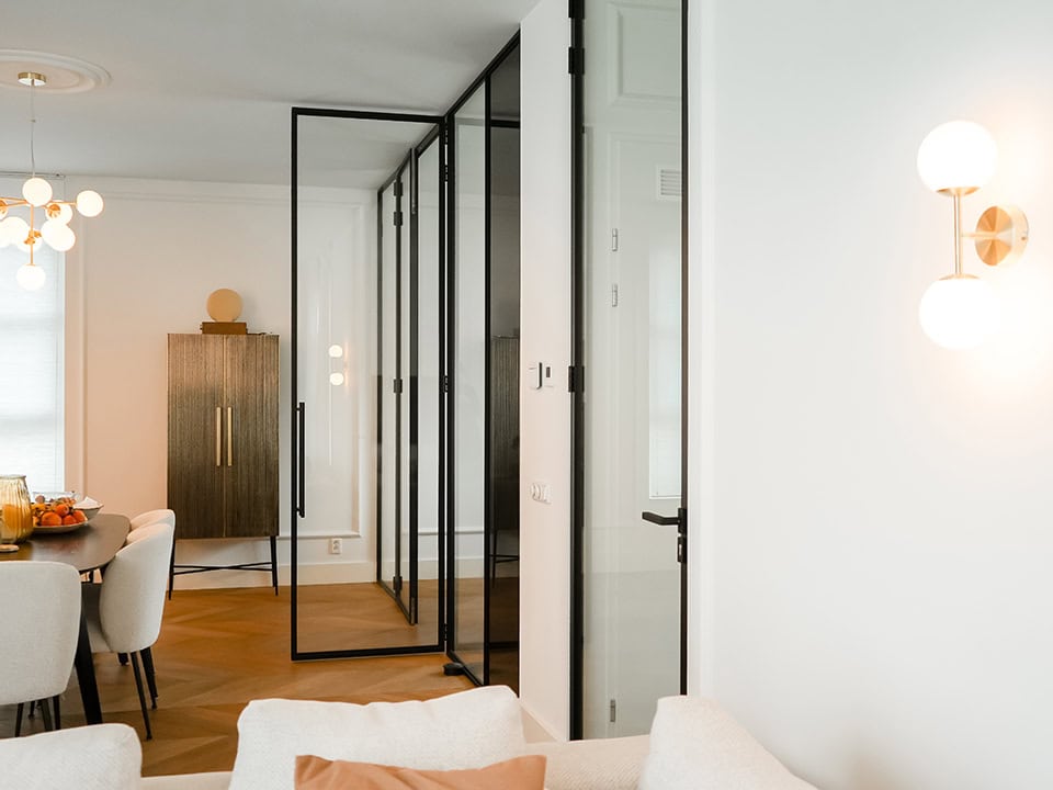 Elegante stalen deuren en wanden op maat in een modern interieur met witte muren en houten vloeren, perfect voor een stijlvolle woning of kantoor.