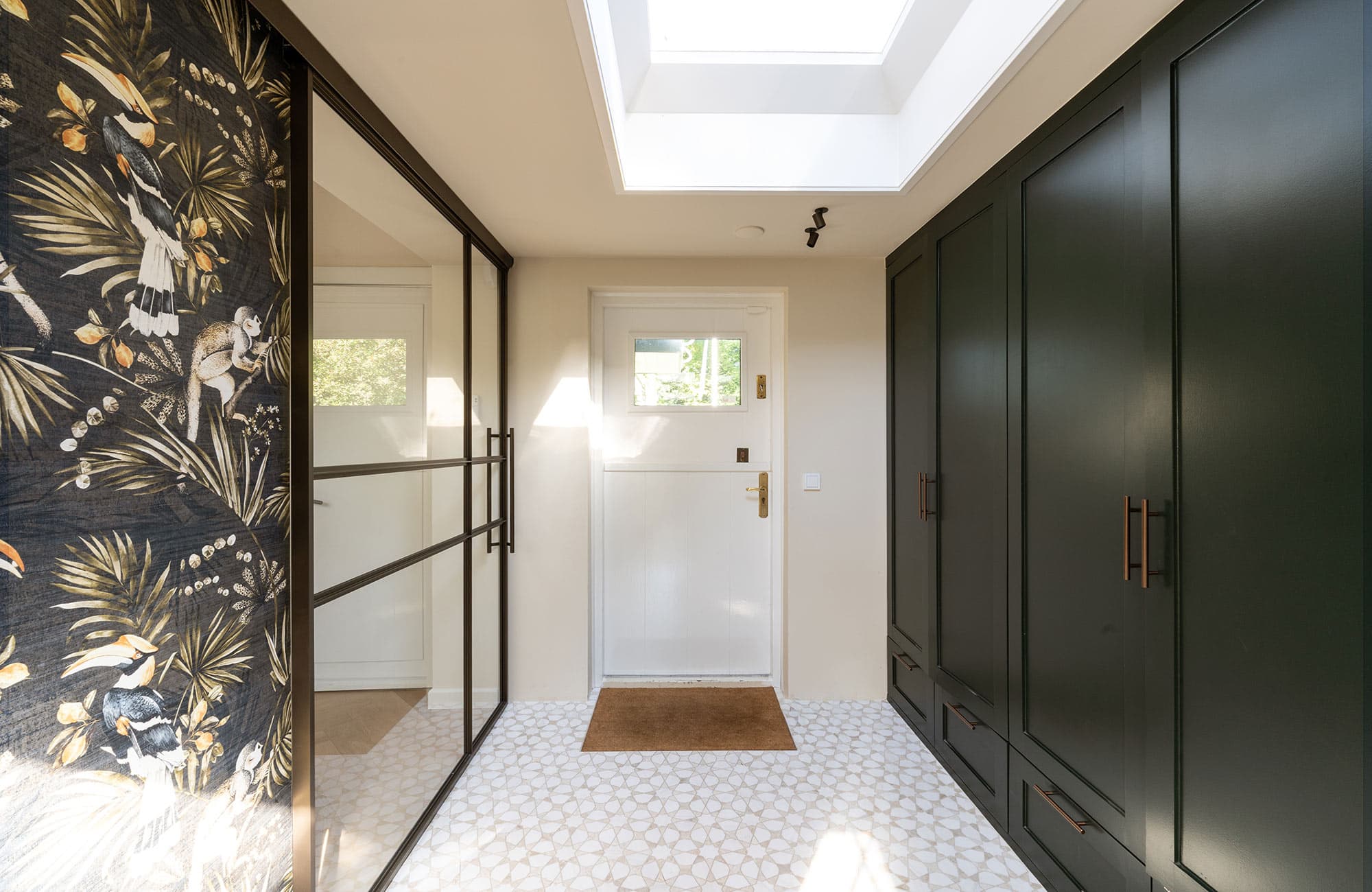 Interieur van een moderne inloopkast met zwarte stalen schuifdeuren, witte muren, een plafondraam en een houten deurmat, perfect voor stijlvolle woninginrichting.