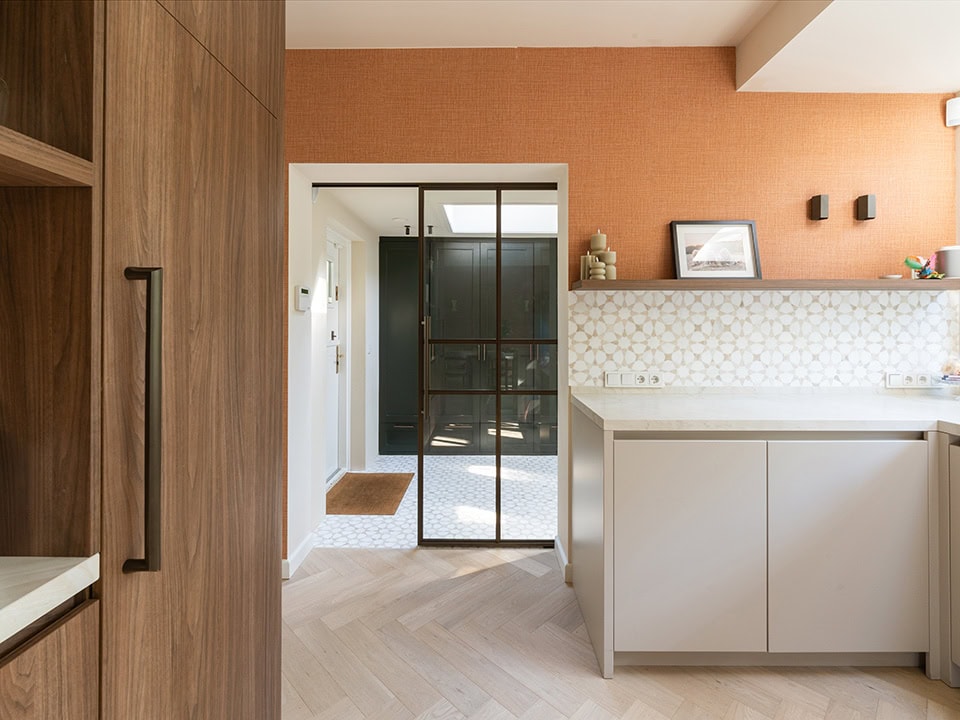 Moderne stalen schuifdeur in keuken, scheidt de keuken van de hal, met zwart metalen frame en glas, voor een strakke en functionele indeling.