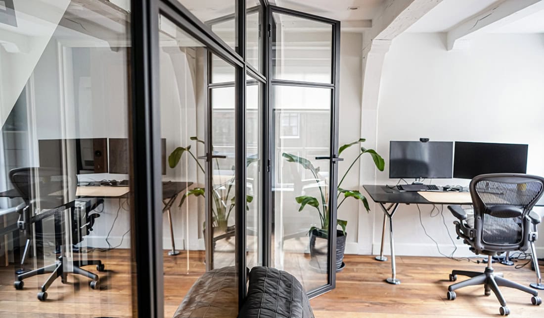 Kantoorruimte met stalen en glazen scheidingswanden, werkplekken en computers, modern en licht interieur, geschikt voor zakelijke omgevingen.