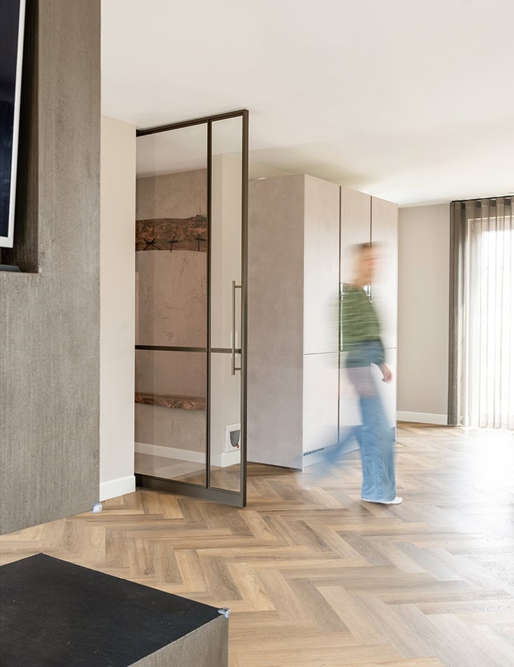 Moderne stalen deur met glas in een eigentijdse woonkamer, perfect voor stijlvolle scheiding en privacy, met natuurlijke lichtinval en houten vloer.