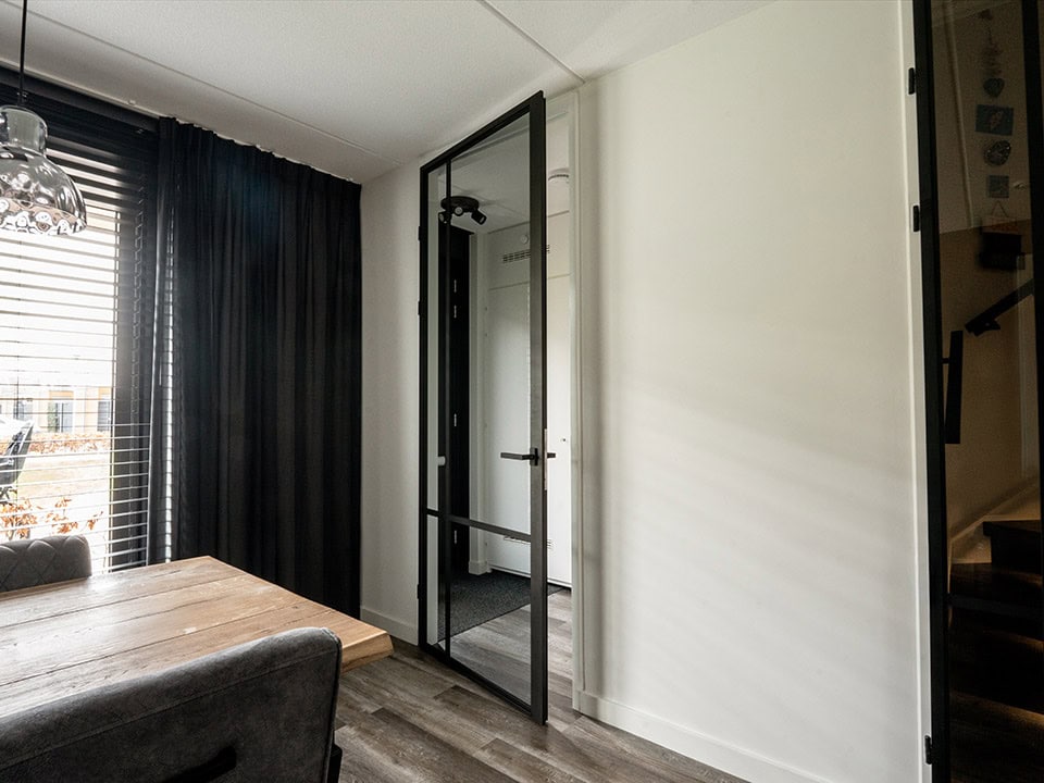 Moderne stalen deur met glas in een eigentijdse woonkamer, ideaal voor scheiding van ruimtes en het toevoegen van industriële stijl.