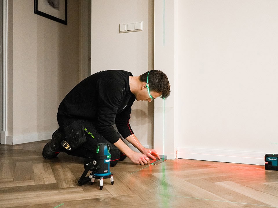 Technicus installeert een stalen schuifdeur met behulp van een laser en gereedschap, gericht op precisie en vakmanschap voor hoogwaardige stalen deuren en wanden.