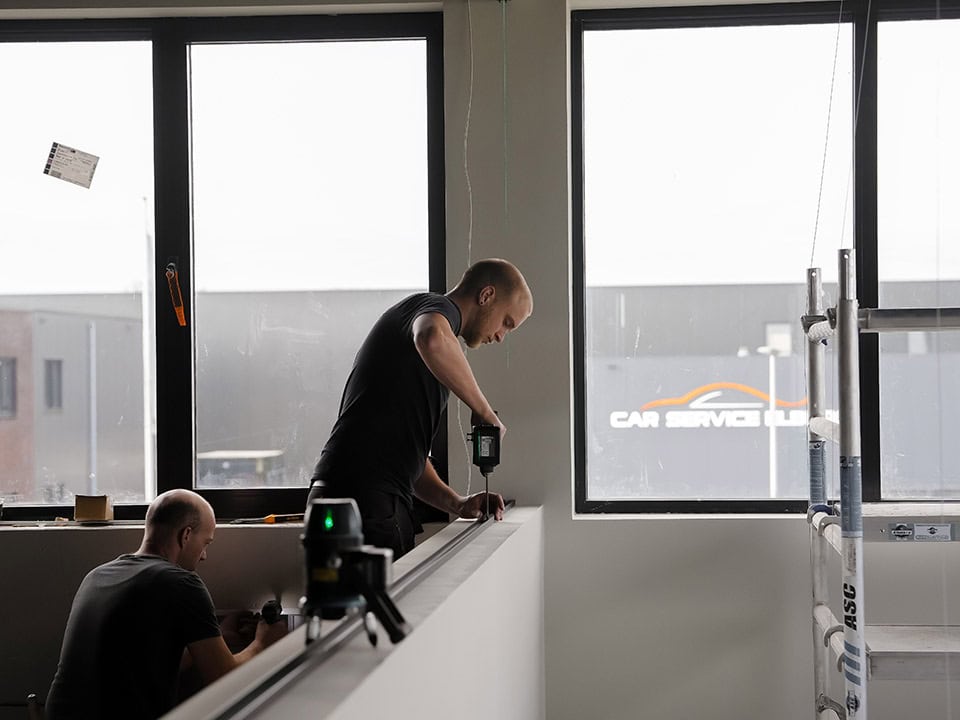Vakmensen installeren stalen deuren en wanden op maat in een modern interieur, met grote ramen en natuurlijke lichtinval, voor een strakke en duurzame afwerking.