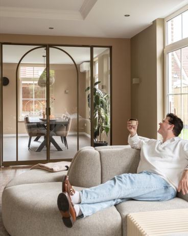 Luxe woning met stalen deuren en wanden op maat, moderne interieurafwerking, natuurlijke lichtinval, comfortabele zithoek, stijlvolle woonruimte.