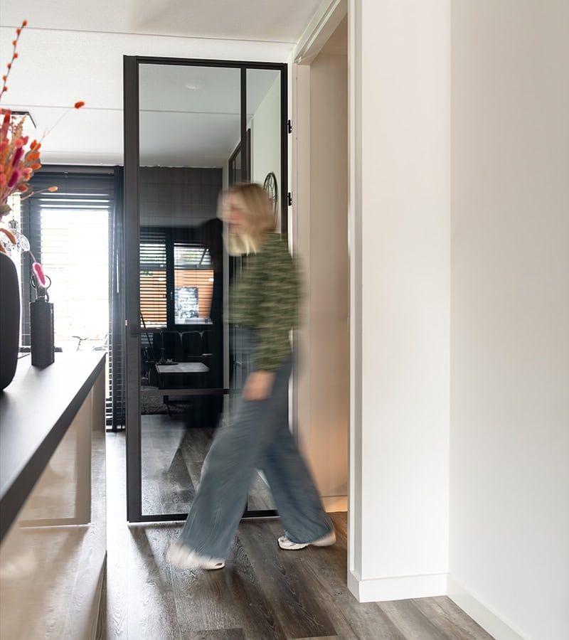 Moderne aluminium schuifdeur met zwart frame en glazen panelen in een eigentijdse woning, ideaal voor scheiding van ruimtes en lichtdoorlatendheid.