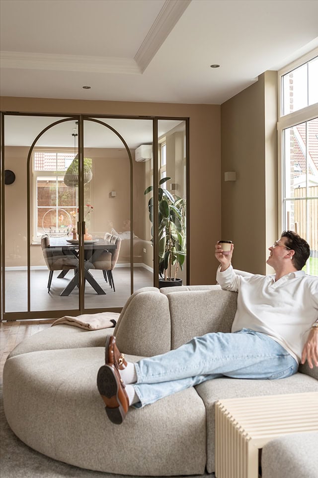 Luxe woonkamer met stalen schuifdeur en natuurlijke lichtinval, modern interieur met comfortabele zithoek en grote ramen voor een open sfeer.