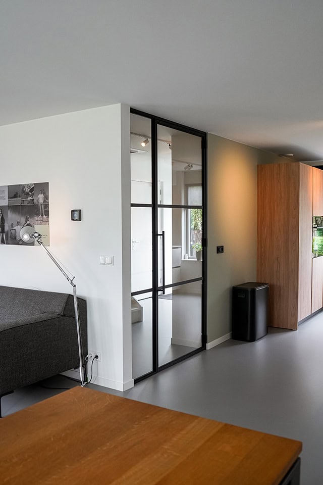 Moderne stalen schuifdeur met glazen panelen in een eigentijdse woning, ideaal voor scheiding van ruimtes en designaccent.