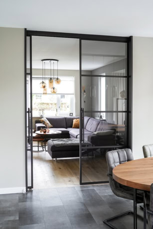 Moderne stalen schuifdeur met glazen panelen, ideaal voor scheiding van woon- en eetkamer, op maat gemaakt voor stijlvolle interieurs.