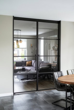 Moderne stalen schuifdeur met glazen panelen, ideaal voor scheiding van woonruimtes en het toevoegen van industriële stijl aan het interieur.