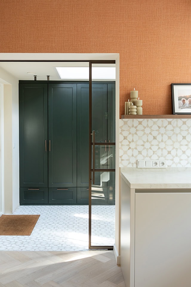 Moderne stalen schuifdeur in keuken met groene kasten en witte tegels, ideaal voor op maat gemaakte stalen deuren en wanden.
