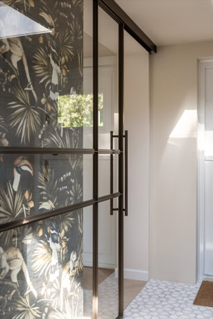 Moderne stalen schuifdeur met zwarte frame en glas, passend bij hoogwaardige stalen deuren en wanden op maat, in een eigentijdse woning.