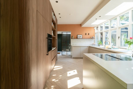 Lichte moderne keuken met grote ramen, witte kasten, houten wand en uitzicht op tuin, perfect voor stijlvolle woonruimtes en natuurlijk licht.