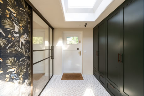 Moderne inloopkast met zwarte kasten en glazen schuifdeuren, veel natuurlijk licht, stijlvolle en functionele opbergruimte, perfect voor een luxe interieur.