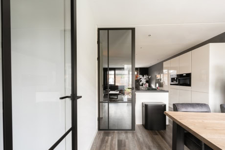 Strakke stalen deur met glas in moderne keuken, perfect voor op maat gemaakte stalen deuren en wanden, passend bij hoogwaardige aluminium oplossingen.
