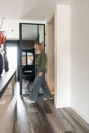 Moderne stalen deur met glas tussen woonkamer en kantoorruimte, strakke afwerking en minimalistisch design, geschikt voor op maat gemaakte stalen deuren en wanden.