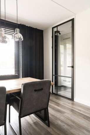 Strakke stalen deur met glas in een modern interieur, perfect voor op maat gemaakte stalen deuren en wanden, passend bij hoogwaardige aluminium en stalen deuroplossingen.